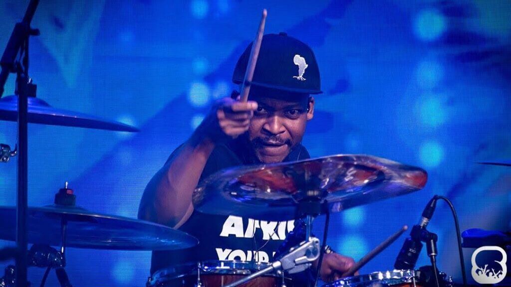 man playing drums wearing a cap