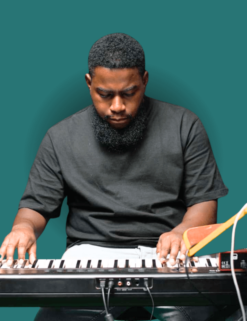 A man with beard wearing a black t-shirt playing a piano